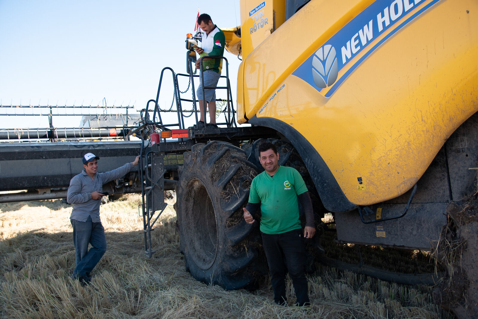 Equipo de Agro Petró junto a una cosechadora New Holland